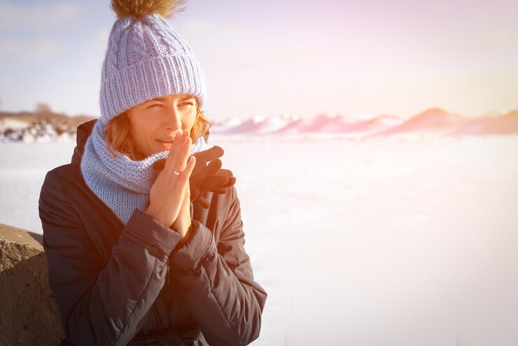 Foto o retrato do estilo de vida da moda da jovem mulher da moda vestida com roupas quentes e elegantes aquece as mãos e congela no inverno retrato de uma mulher alegre ao fundo neve branca e montanhas congeladas