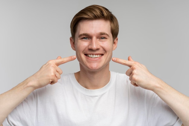 O retrato do homem alegre feliz aponta o dedo indicador no sorriso mostra os dentes brancos