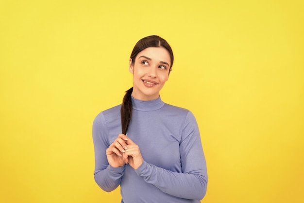 O retrato sorridente da mulher toca o cabelo nas emoções de fundo amarelo