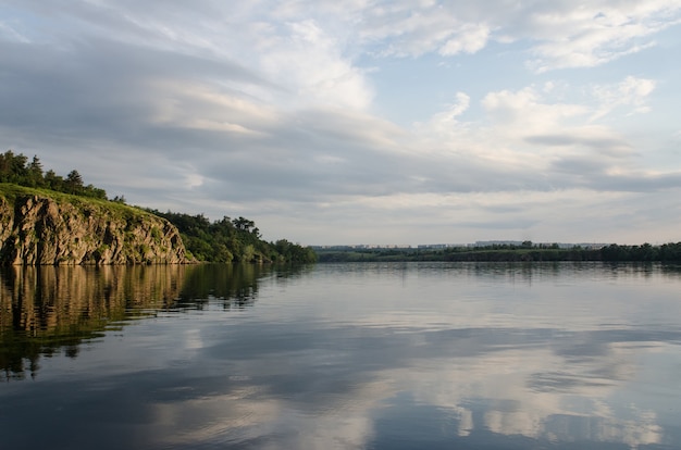 O rio da rocha na luz laranja do sol no fundo do céu azul, leito do rio