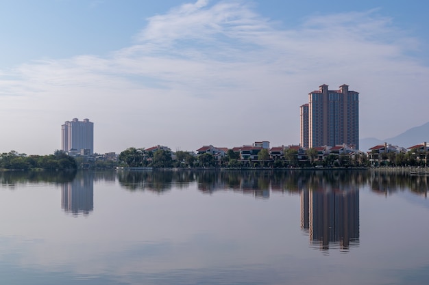 O rio reflete a bela paisagem de ambos os lados, com árvores e casas verdes.