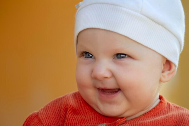 O rosto de um bebê alegre de seis meses. Bebê feliz com um chapéu.