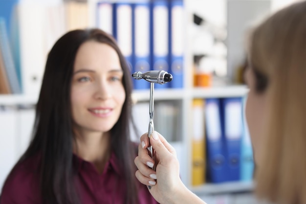 O rosto de uma mulher observando o martelo de um neurologista