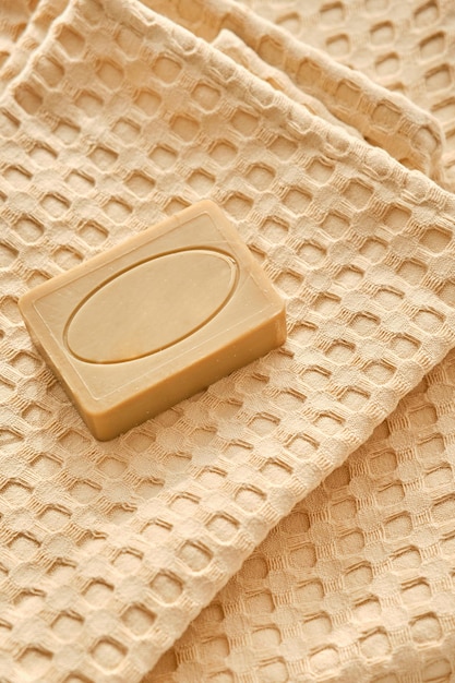 O sabonete artesanal de oliva natural repousa sobre uma composição de toalha de musselina natural em bege