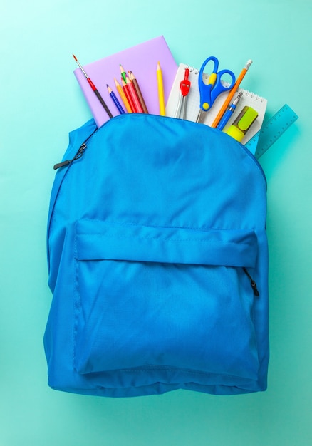 Foto o saco da escola. mochila com material para a escola em fundo azul. copie o espaço para o texto.