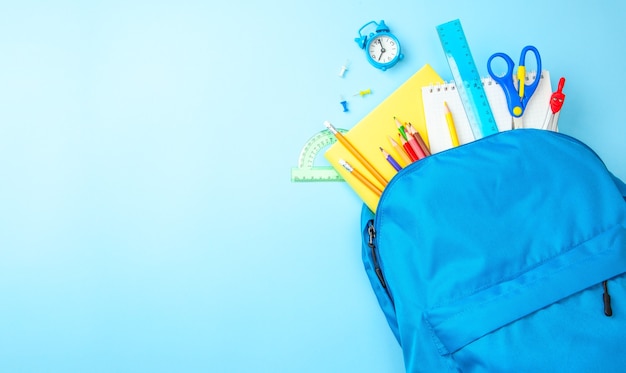 O saco da escola. Mochila com material para a escola em fundo azul. Copie o espaço para o texto