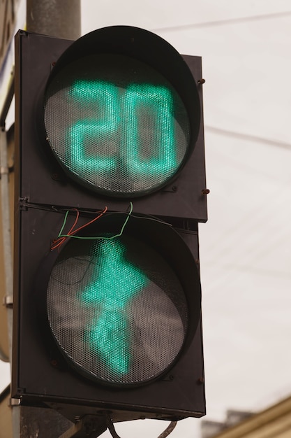 Foto o semáforo verde e os pedestres estão acesos no semáforo com fios para fora. faixa de pedestres na cidade. o número 20 no semáforo deixa claro que os pedestres atravessam a rua por vinte segundos