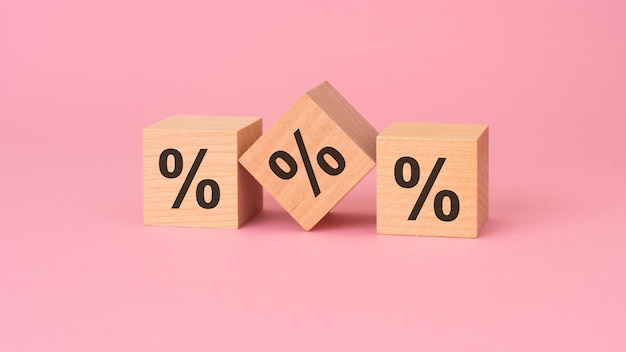 o sinal de porcentagem em cubos de madeira fundo rosa
