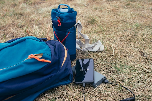 O smartphone é carregado com um carregador portátil. Power Bank carrega o telefone ao ar livre com uma mochila para turismo na natureza.