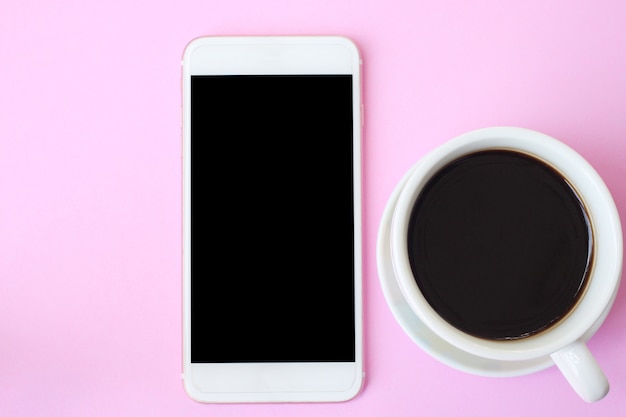 O smartphone e o café da vista superior no assoalho cor-de-rosa e têm o espaço da cópia.