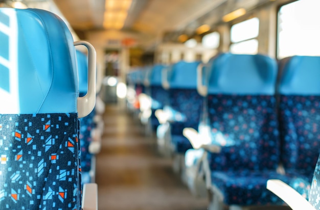 O sol brilha em assentos vazios no trem, conceito abstrato de viagem de trem com profundidade rasa de foto de campo apenas fecha o foco da cadeira
