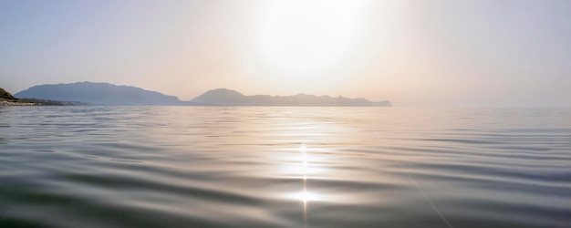 O sol noturno da paisagem marítima se põe atrás das montanhas ao fundo