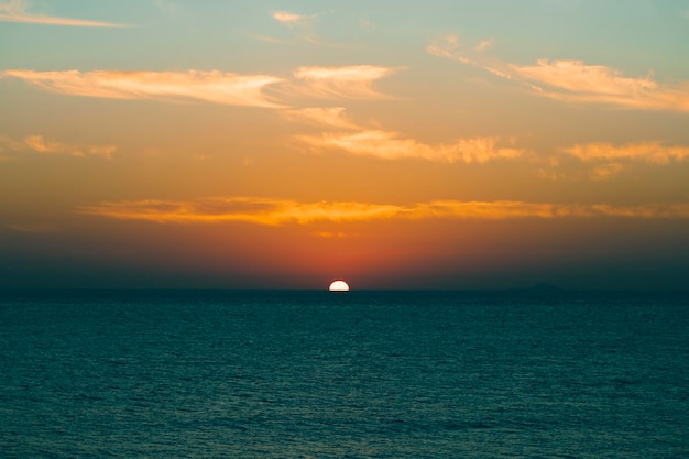 O sol se põe sobre o oceano com o horizonte em primeiro plano.