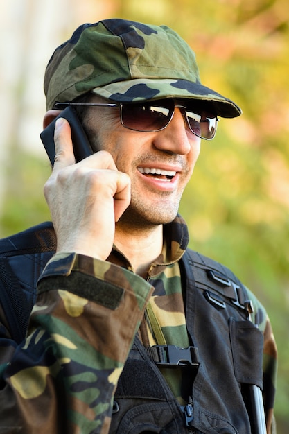 O soldado de uniforme sorridente está falando ao telefone.