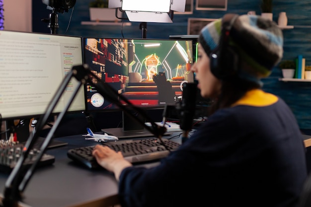 O streamer Pro usa fones de ouvido e olha para um monitor potente com o bate-papo do jogo aberto. Streaming online cibernético realizando torneio virtual usando tecnologia de rede sem fio