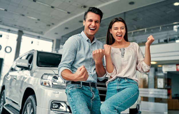 Foto o sucesso da visita à concessionária. jovem casal feliz escolhe e compra um carro novo para a família.