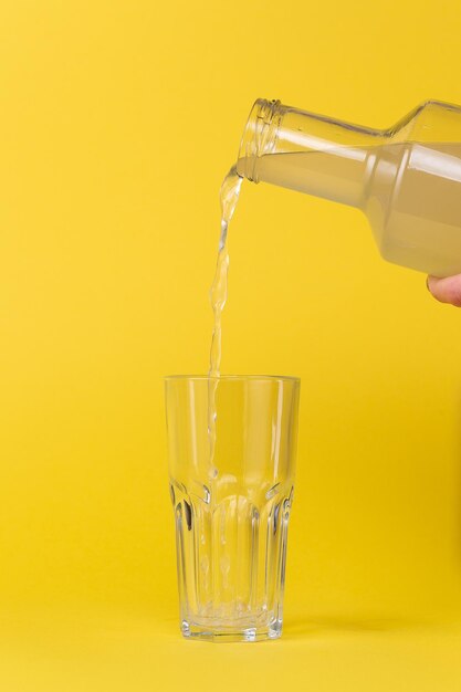 O suco de limão é derramado em um copo com uma garrafa de vidro