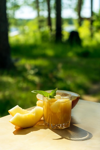 O suco de melão com hortelã em uma jarra de vidro sobre a mesa. Melão de fami