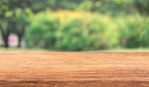 O tampo da mesa de madeira no fundo abstrato verde do borrão para indica seus produtos