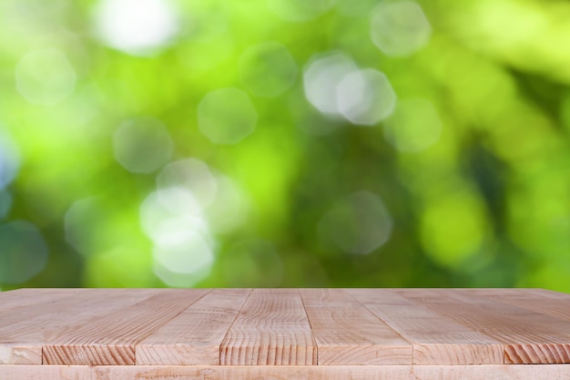 O tampo da mesa de madeira no fundo verde bokeh pode ser usado para montagem ou exibir seus produtos