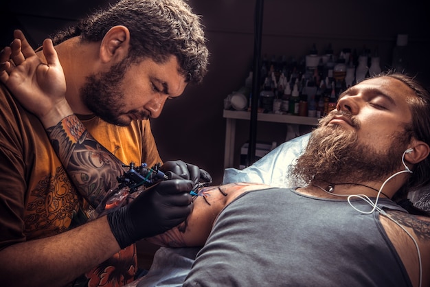 O tatuador profissional cria uma tatuagem no estúdio de tatuagem.