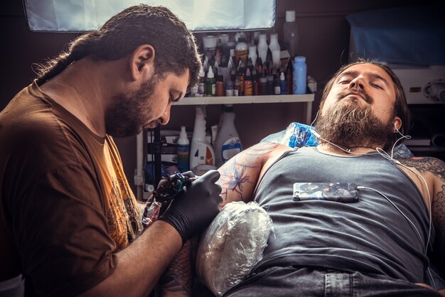 O tatuador profissional faz tatuagem no estúdio de tatuagem.