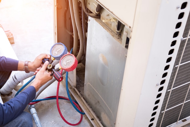 O técnico está verificando o ar condicionado, medindo o equipamento para encher os aparelhos.