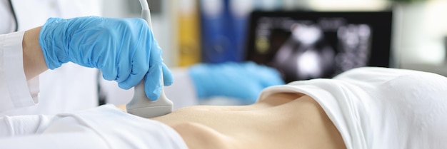 O técnico ultrassonografista segura a sonda de ultrassom para diagnosticar a condição da mulher grávida olhando para a mulher