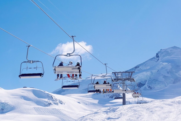 O teleférico acima da montanha coberta de neve contra o céu azul