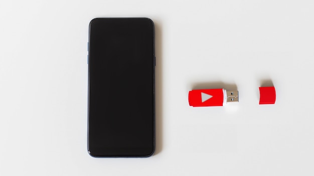 O telefone e o pen drive em uma superfície branca