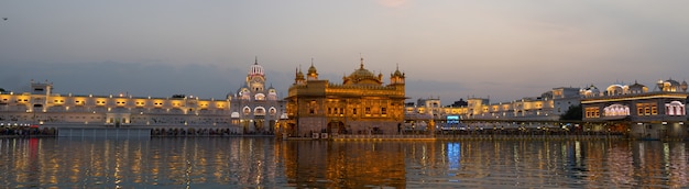 O Templo Dourado em Amritsar, Punjab, Índia, o ícone mais sagrado e local de culto da religião Sikh. Iluminado na noite, refletido no lago.