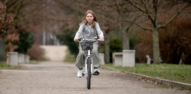 O tempo quente vê uma menina a andar de bicicleta pelo parque da primavera.