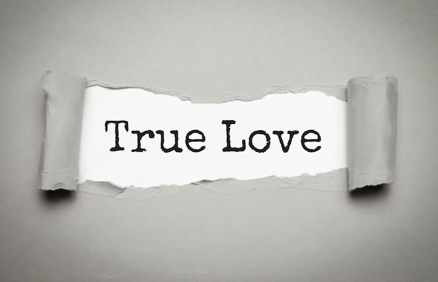 O texto True Love aparecendo atrás de papel castanho rasgado