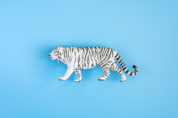 O tigre, símbolo do ano 2022. brinquedo de plástico branco figura tigre sobre um fundo azul. vista do topo