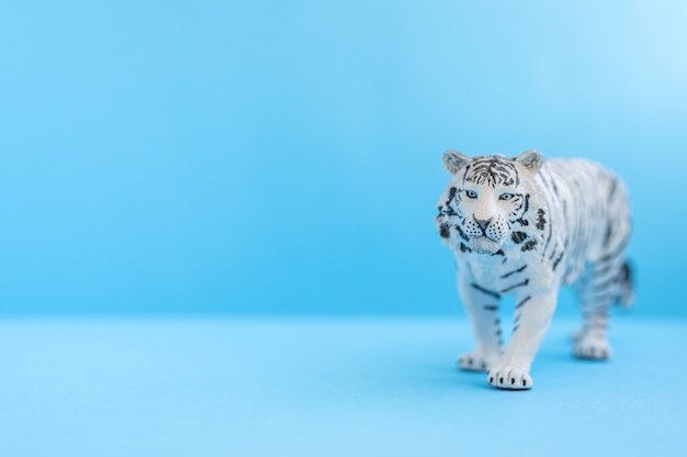 O tigre, símbolo do ano 2022. figura de brinquedo de plástico branco tigre sobre um fundo azul. espaço para texto