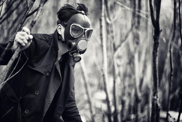 O tipo com o casaco e a máscara de gás. Retrato pós-apocalíptico asiático mascarado de radiação. O rapaz é coreano com uma máscara de envenenamento com gases. Máscara pós-nuclear no asiático.
