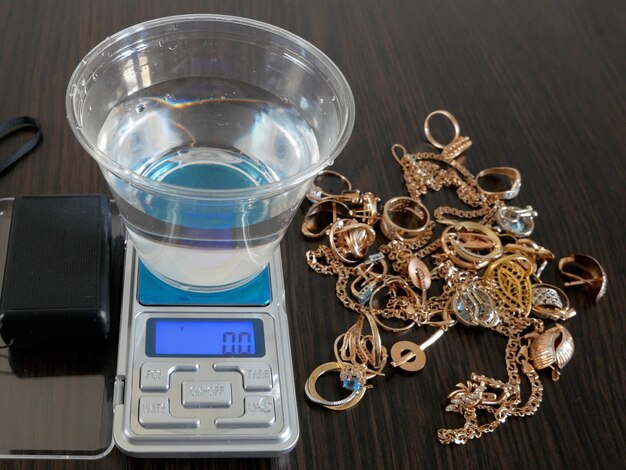 Foto o trabalhador da loja de penhores determina o anel de jóias de ouro usando o método de pesagem hidrostática