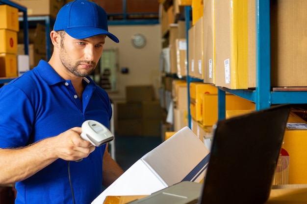 O trabalhador de entrega segurando a caixa para enviar ao cliente por cheque com scanner