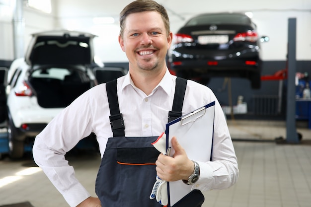 O trabalhador de sorriso do homem repara o retrato do serviço do carro.