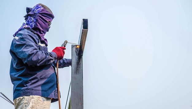 O trabalhador do soldador usa ferramentas de soldagem de aço soldando grandes barras de aço no canteiro de obras