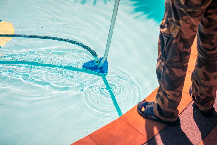 O trabalhador está a limpar uma enorme piscina transparente com um aspirador subaquático