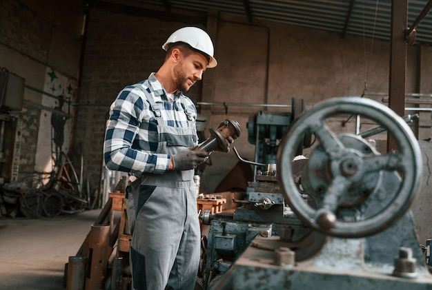 Foto o trabalhador masculino da fábrica de processamento de metal de uniforme está dentro de casa