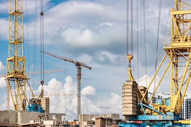 O trabalho de guindastes de torre no contexto do céu do sol. construção de moradias modernas. engenharia industrial. construção de hipotecas de habitação.