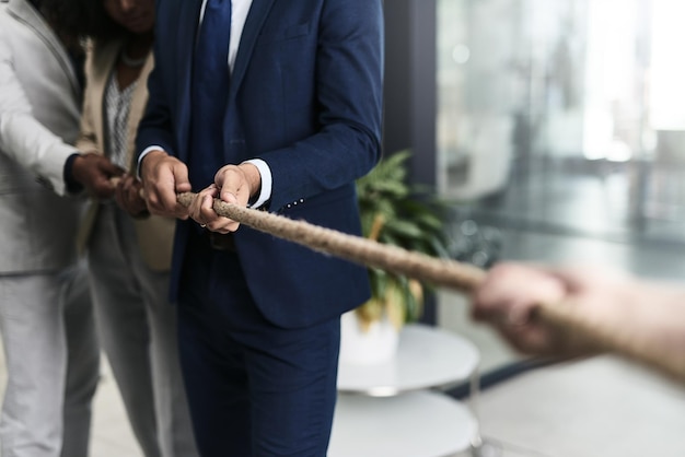 O trabalho em equipe pode derrotar qualquer desafio Captura de um grupo de empresários irreconhecíveis puxando uma corda em um escritório