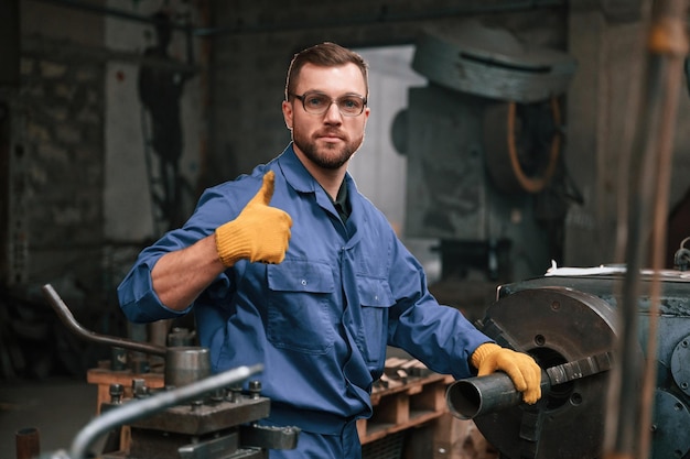 Foto o trabalho está feito. o trabalhador da fábrica de uniforme azul está dentro de casa.