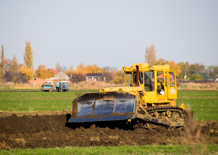 Foto o tractor amarelo com grederom anexado faz o nivelamento do solo