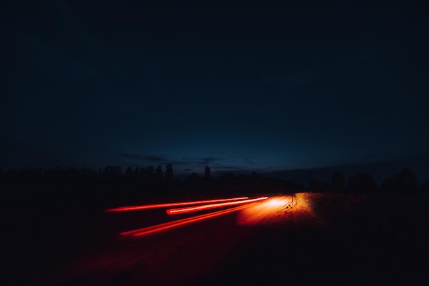 O traiol das luzes do carro com longa exposição no campo à noite