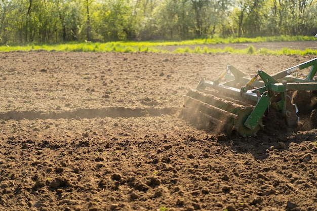 O trator atravessa o campo e cultiva a terra O veículo agrícola trabalha no campo A semeadura é o processo de plantar sementes no solo no início da primavera