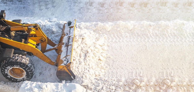 O trator laranja remove a neve da estrada e limpa a calçada Remoção de neve após a queda de neve