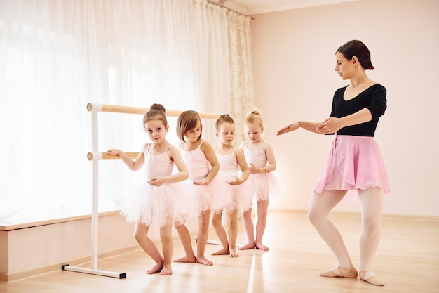 O treinador ensina as crianças pequenas bailarinas se preparando para o desempenho praticando movimentos de dança